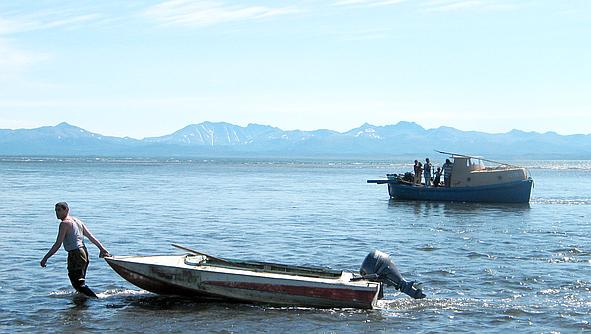 Бот Славы Буялова сел на мель, и матрос Леша готовит к плаванию моторную лодку, поселок Тиличики, Камчатка, 2008 год